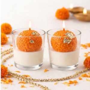 Orange ladoo shaped candle in glass votive for Ganesh Chaturthi and Diwali decoration