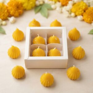 Handcrafted yellow modak candles arranged around a festive Ganesh Chaturthi gift box