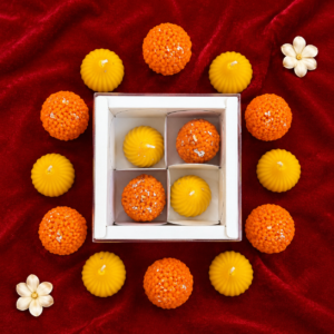 Festive box of handcrafted laddoo and modak candles arranged on red fabric